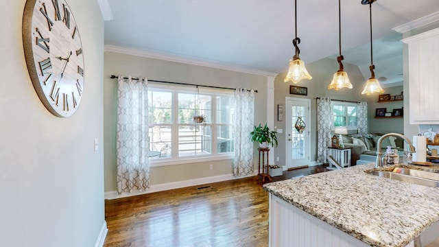 kitchen featuring white cabinets, dark wood-type flooring, light stone countertops, crown molding, and a sink