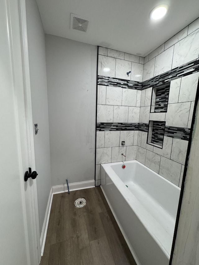 full bathroom with baseboards, visible vents, wood finished floors, and shower / bathtub combination