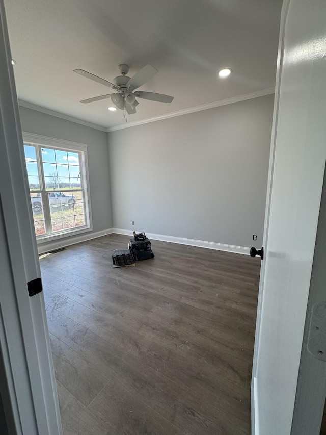 empty room with ornamental molding, dark wood-type flooring, and baseboards