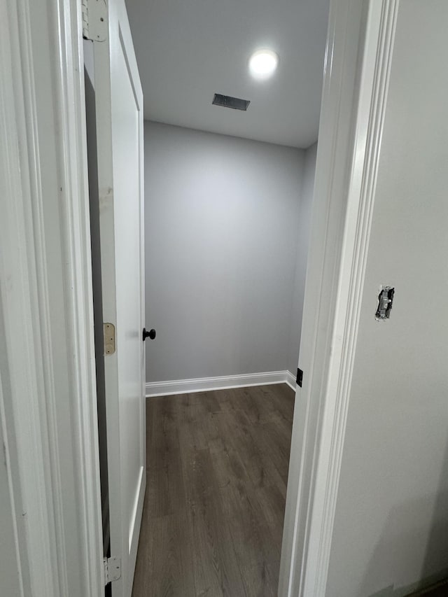 hallway with dark wood-style floors, visible vents, and baseboards