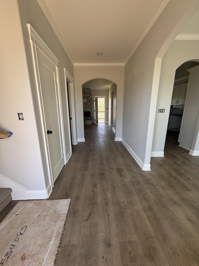 hallway featuring arched walkways, dark wood-style flooring, and crown molding