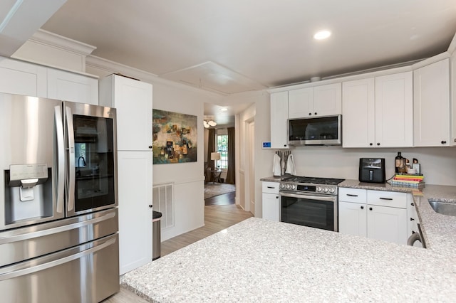 kitchen with a peninsula, visible vents, appliances with stainless steel finishes, and white cabinets