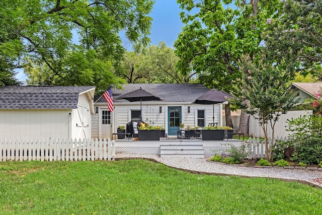 view of front of house featuring a front lawn, roof with shingles, a wooden deck, and fence