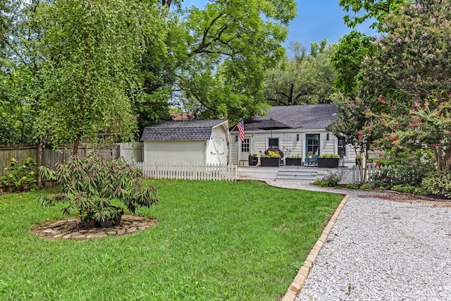 exterior space with a lawn, roof with shingles, fence, an outdoor structure, and a shed