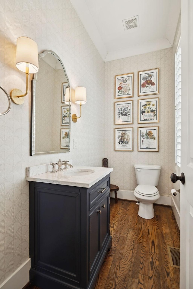 bathroom featuring wallpapered walls, baseboards, visible vents, and wood finished floors