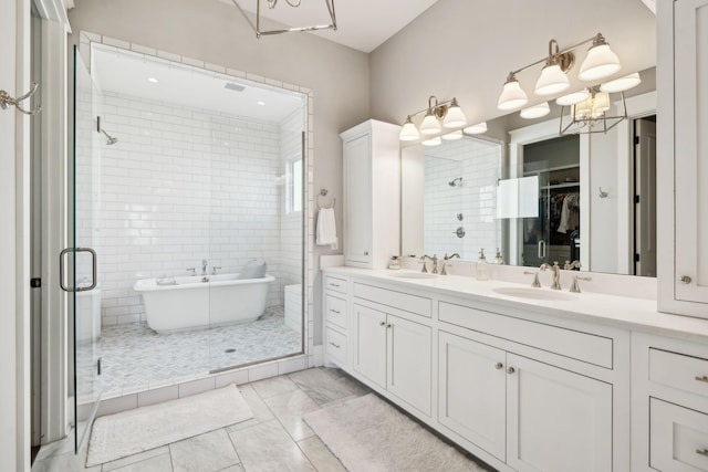 full bathroom with a spacious closet, a sink, a shower stall, and double vanity