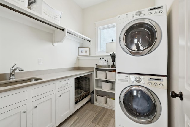 washroom featuring stacked washer and dryer, a sink, and cabinet space