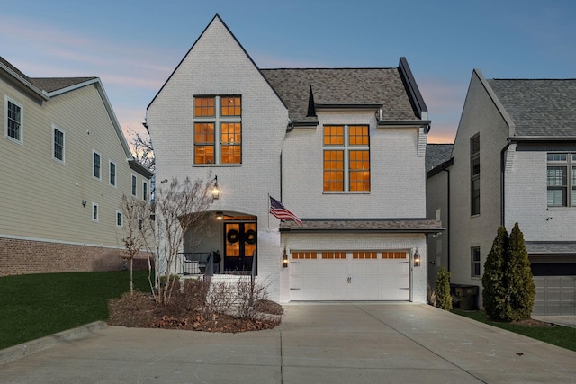 view of front facade featuring a garage, a shingled roof, concrete driveway, and brick siding