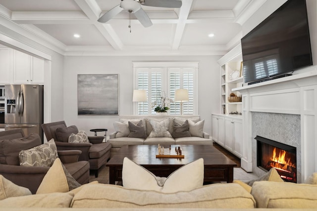 living room featuring built in shelves, coffered ceiling, ornamental molding, beamed ceiling, and a tiled fireplace