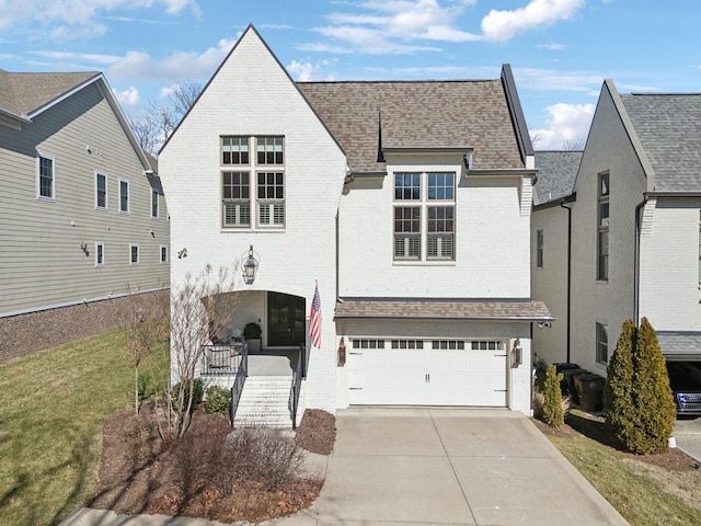 view of front of house featuring brick siding, a shingled roof, concrete driveway, a front yard, and a garage