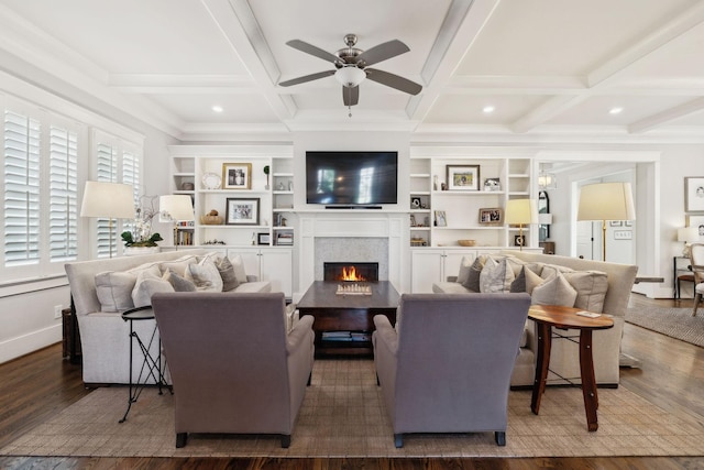 living room with coffered ceiling, a ceiling fan, wood finished floors, a lit fireplace, and beam ceiling