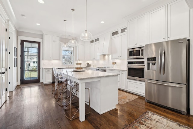 kitchen featuring tasteful backsplash, white cabinets, dark wood-style floors, stainless steel appliances, and premium range hood