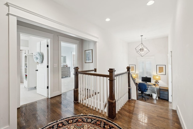 corridor with baseboards, wood finished floors, an upstairs landing, a chandelier, and recessed lighting