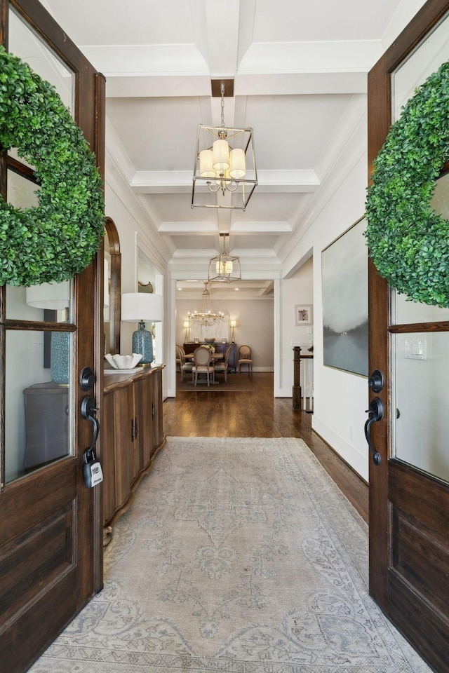 entrance foyer featuring a notable chandelier, coffered ceiling, wood finished floors, baseboards, and beamed ceiling