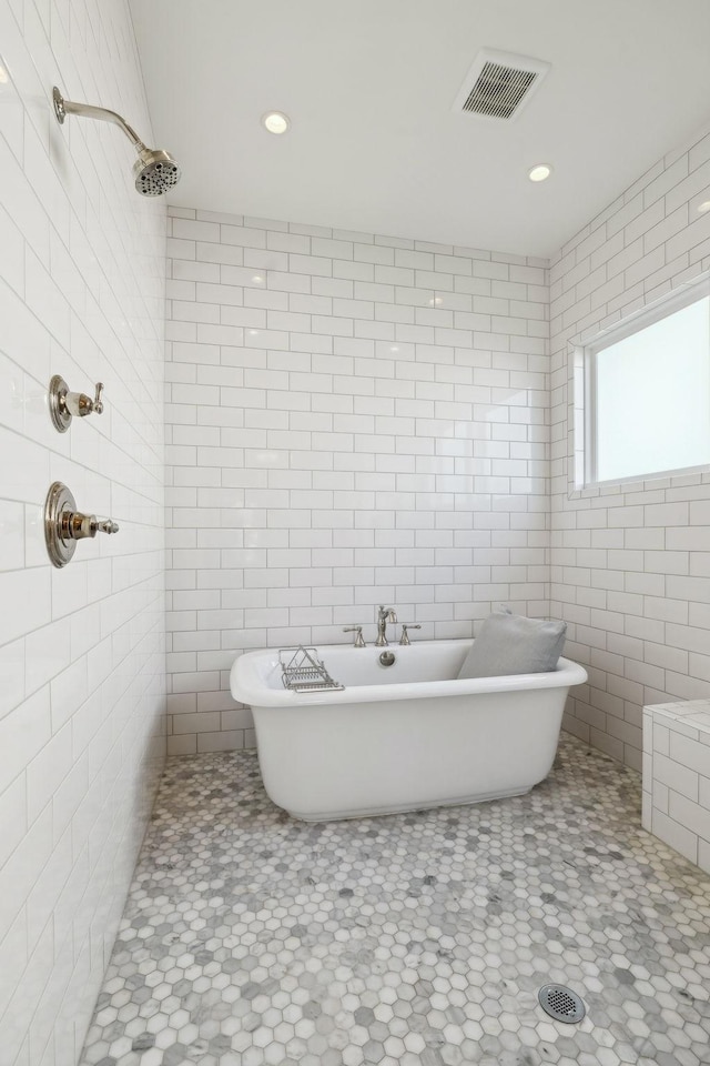 bathroom with visible vents, a tile shower, and tile walls