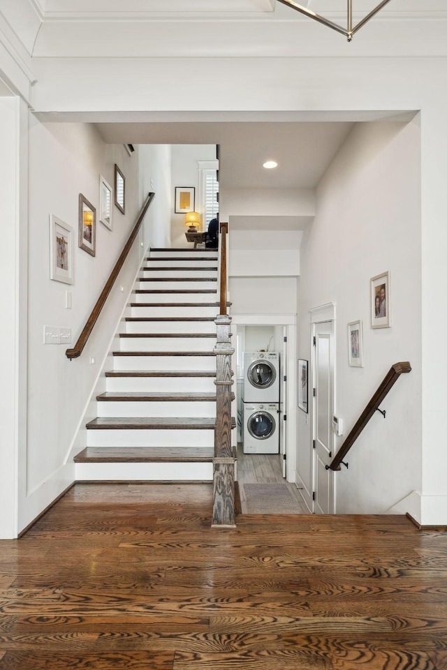 staircase with stacked washer and dryer, baseboards, and wood finished floors