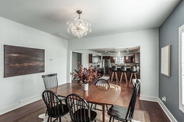 dining space with a chandelier, baseboards, and dark wood-style flooring