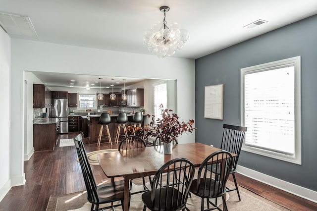 dining space with dark wood finished floors, visible vents, and plenty of natural light