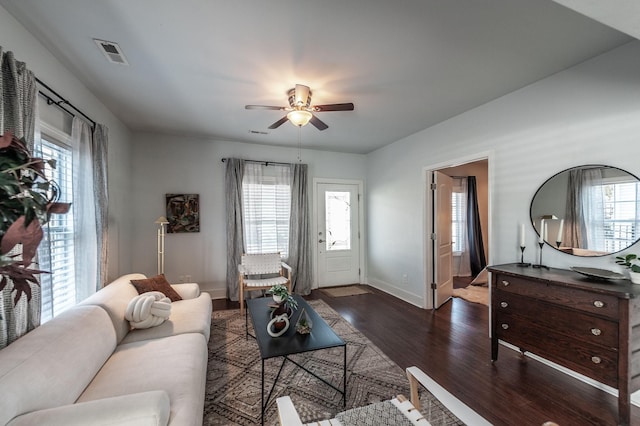 living room featuring visible vents, a healthy amount of sunlight, dark wood-style floors, and a ceiling fan