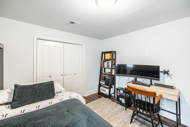 bedroom with visible vents, wood finished floors, a closet, and baseboards