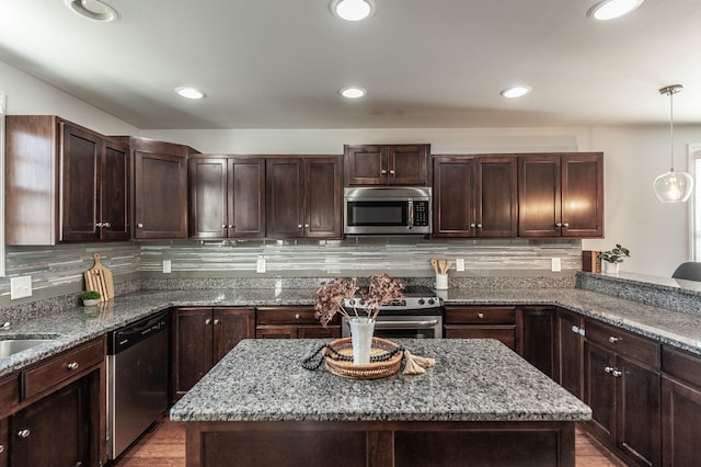 kitchen featuring a kitchen island, dark brown cabinetry, appliances with stainless steel finishes, decorative light fixtures, and tasteful backsplash