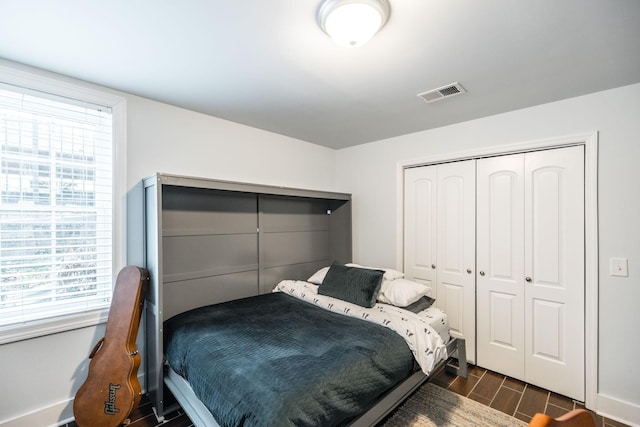 bedroom featuring a closet, visible vents, multiple windows, and wood finish floors