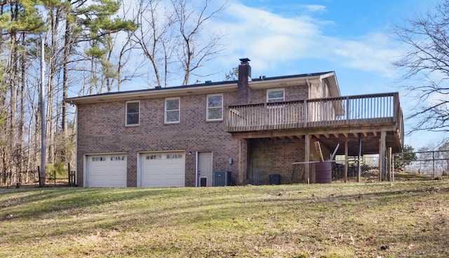 rear view of house with a garage, a wooden deck, a chimney, a yard, and brick siding