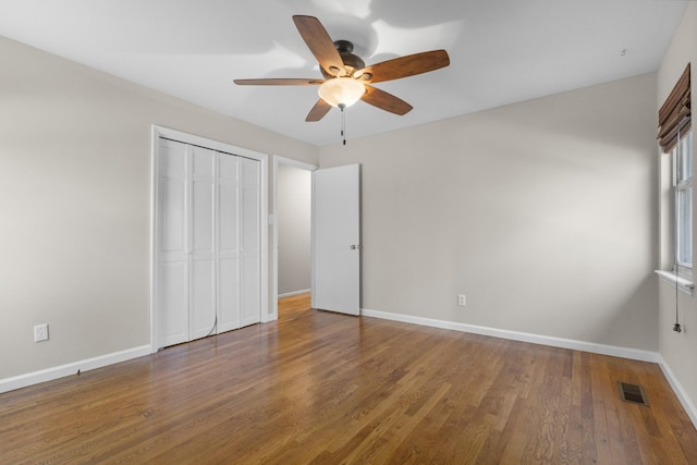 unfurnished bedroom with a closet, visible vents, baseboards, and wood finished floors