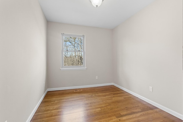 unfurnished room with visible vents, baseboards, and wood finished floors