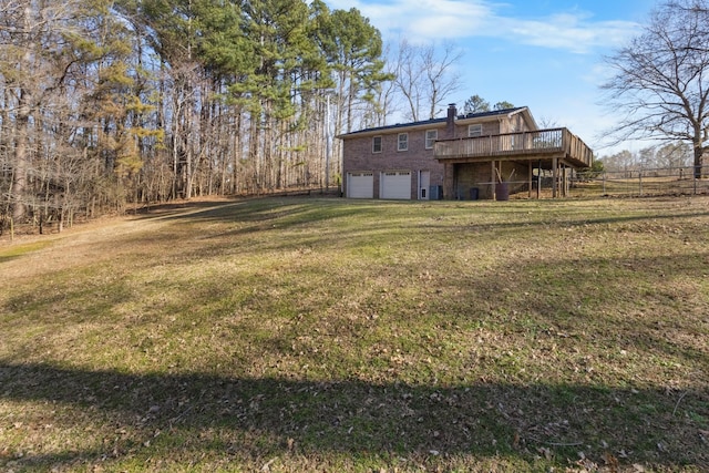 view of yard with an attached garage, a wooden deck, and fence