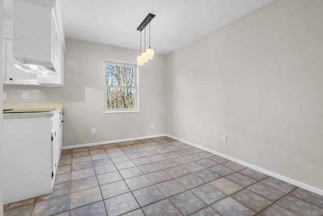 unfurnished dining area with an inviting chandelier, light tile patterned flooring, and baseboards