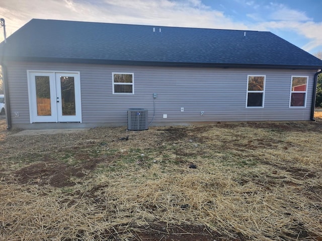 rear view of property with french doors, roof with shingles, and central air condition unit