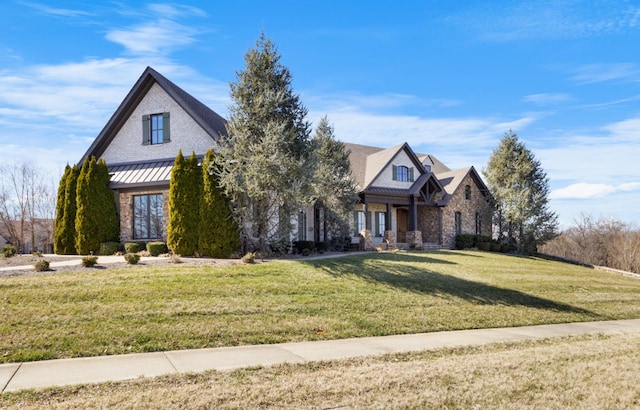 view of front facade featuring stone siding, a front lawn, metal roof, and a standing seam roof