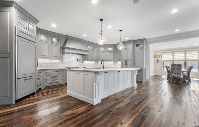 kitchen featuring paneled fridge, gray cabinetry, light countertops, glass insert cabinets, and custom exhaust hood