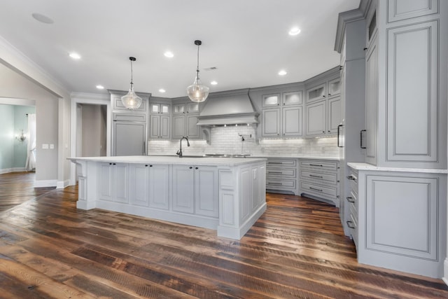 kitchen with gray cabinetry, a center island with sink, custom range hood, a sink, and stainless steel gas cooktop