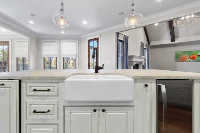 kitchen featuring pendant lighting, a sink, lofted ceiling with beams, white cabinets, and crown molding