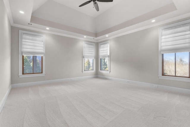 carpeted empty room with recessed lighting, crown molding, a raised ceiling, and baseboards