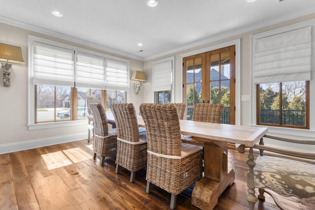 dining space featuring wood finished floors, baseboards, a wealth of natural light, and ornamental molding