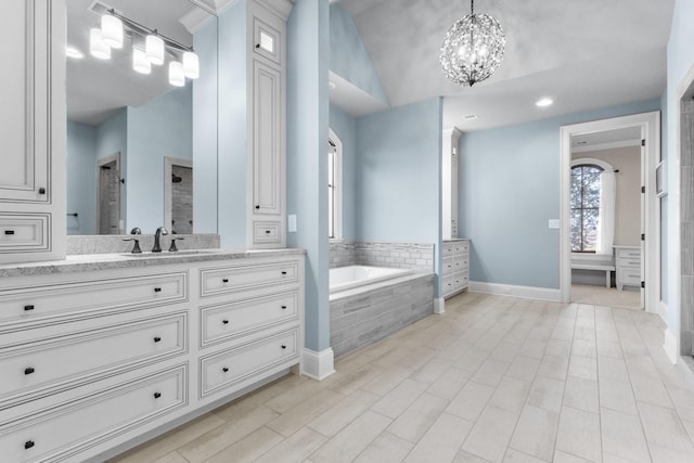 bathroom with a notable chandelier, baseboards, a garden tub, and vanity