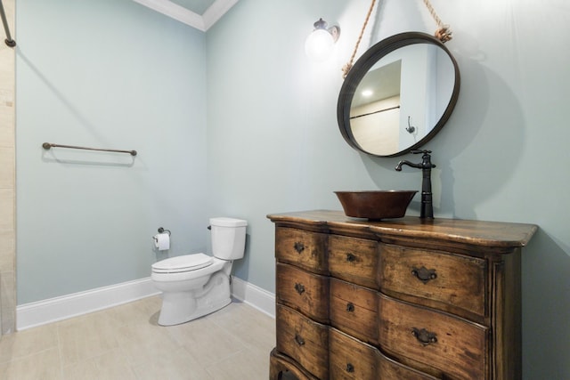 bathroom with baseboards, toilet, ornamental molding, and vanity