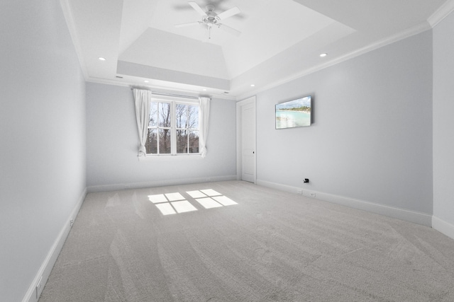 carpeted spare room featuring a tray ceiling, recessed lighting, crown molding, baseboards, and ceiling fan