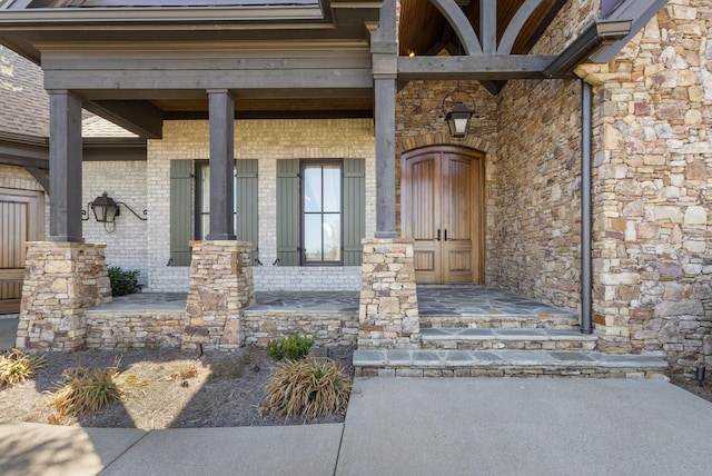 view of exterior entry featuring brick siding and covered porch