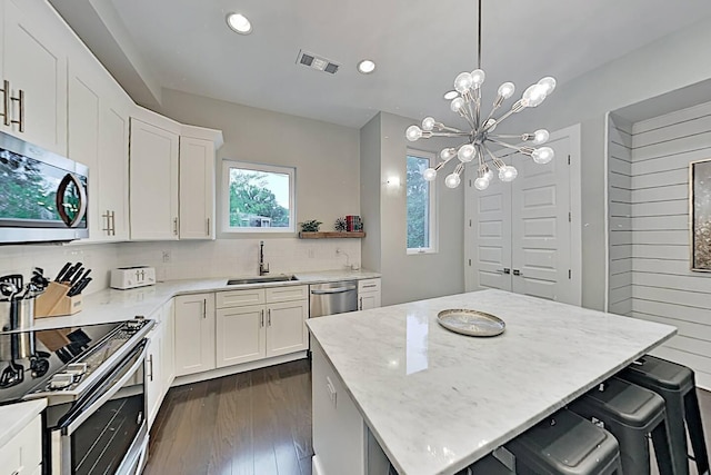 kitchen featuring dark wood-style flooring, stainless steel appliances, backsplash, a sink, and a kitchen island