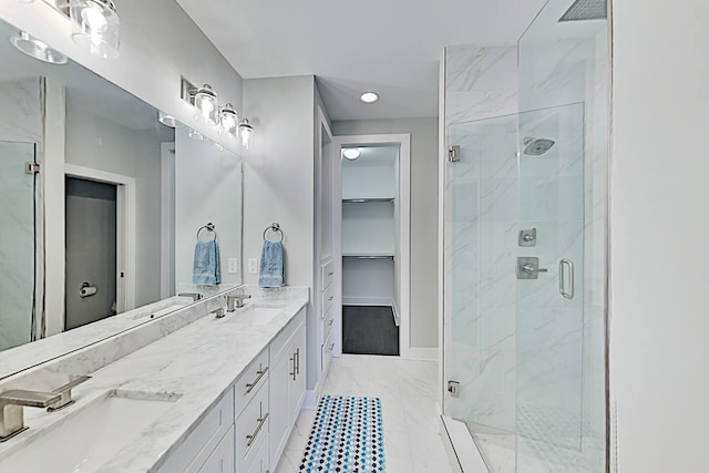 bathroom featuring a sink, a spacious closet, and a marble finish shower