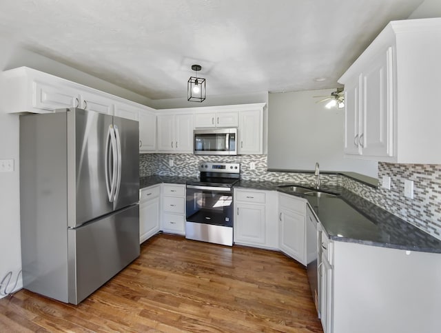 1173 Snoopy Dr, Clarksville, TN 37040 - kitchen with white cabinets, dark countertops, wood finished floors, stainless steel appliances, and a sink