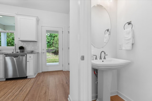 bathroom with a sink, tasteful backsplash, baseboards, and wood finished floors