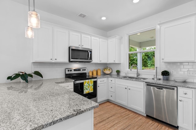 kitchen featuring stainless steel appliances, a sink, white cabinets, decorative backsplash, and light wood finished floors