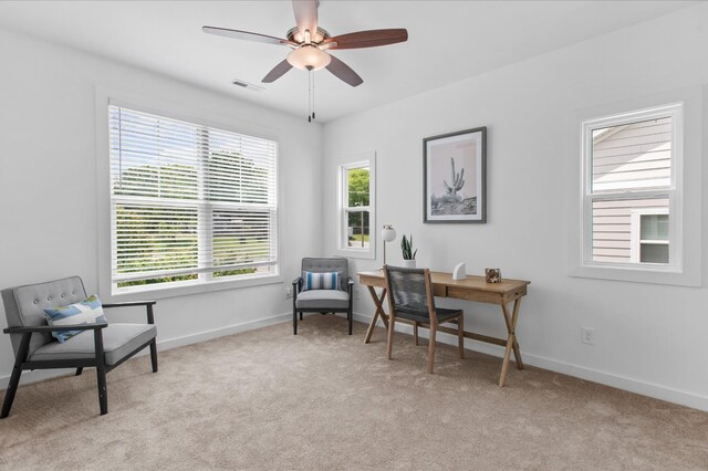 living area featuring light colored carpet, ceiling fan, visible vents, and baseboards