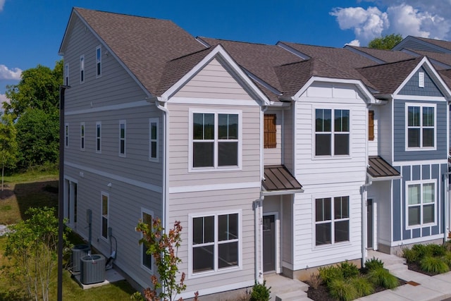 view of front of house with a standing seam roof, metal roof, roof with shingles, and cooling unit