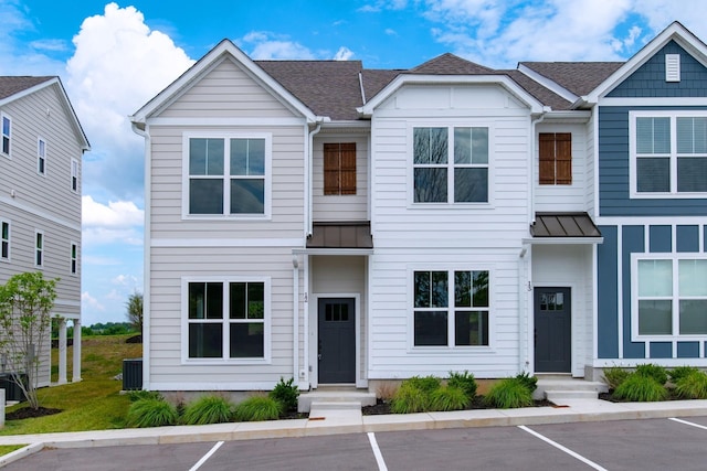 townhome / multi-family property with uncovered parking, a standing seam roof, roof with shingles, and metal roof